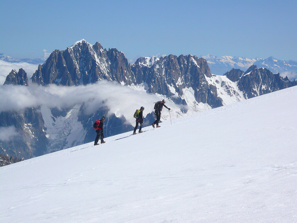 Alpinistes encordés sur une pente de neige lors d'une ascension dans le massif du Mont-Blanc